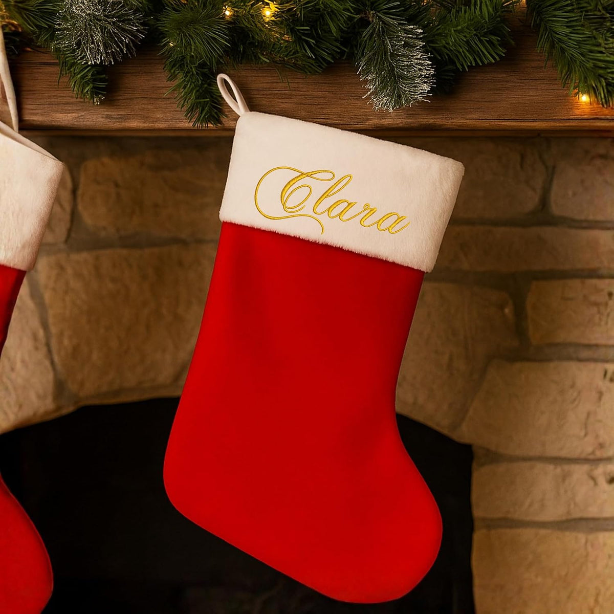 Chaussette de Noël rouge brodée du prénom Clara suspendue à une cheminée décorée
