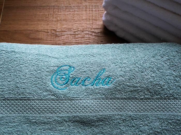 Gros plan du prénom « Sacha » brodé en fil turquoise sur une serviette éponge bleu clair