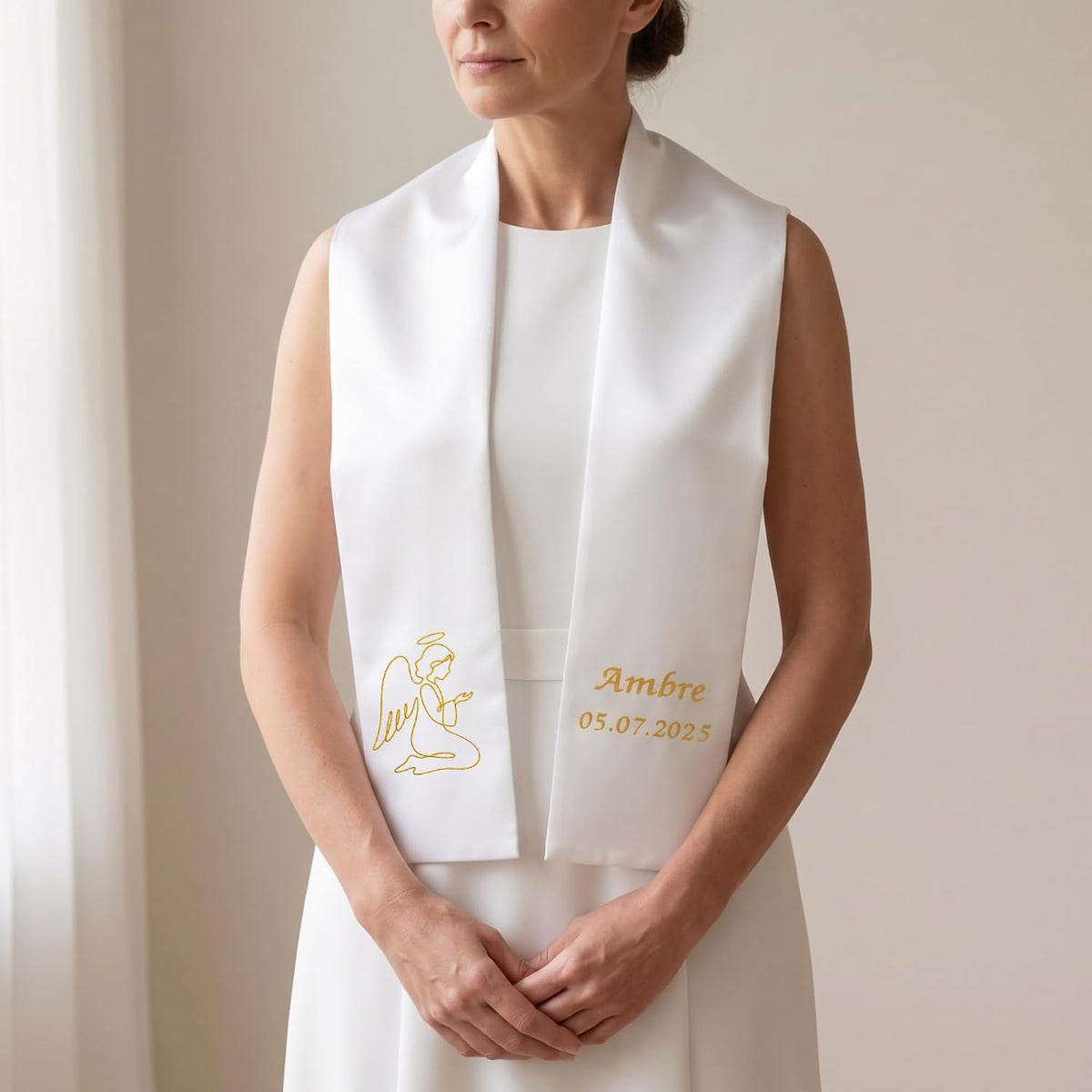 Illustration : femme en robe blanche portant l'étole de baptême brodée d'un ange doré et du prénom « Ambre »