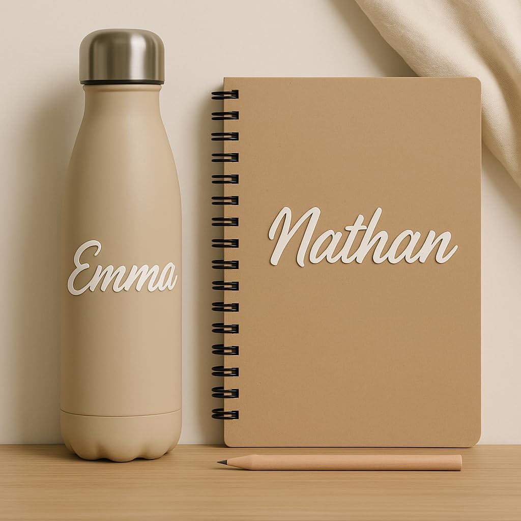 Stickers prénom blancs « Emma » sur une gourde beige et « Nathan » sur un carnet à spirale kraft
