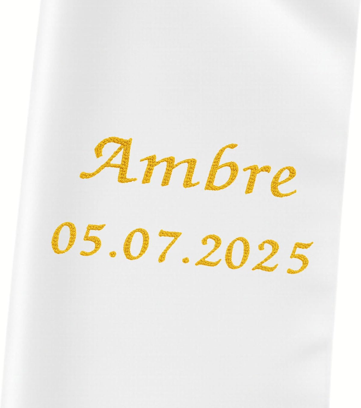 Gros plan du prénom « Ambre » et de la date 05.07.2025 brodés en fil doré sur l'étole de baptême